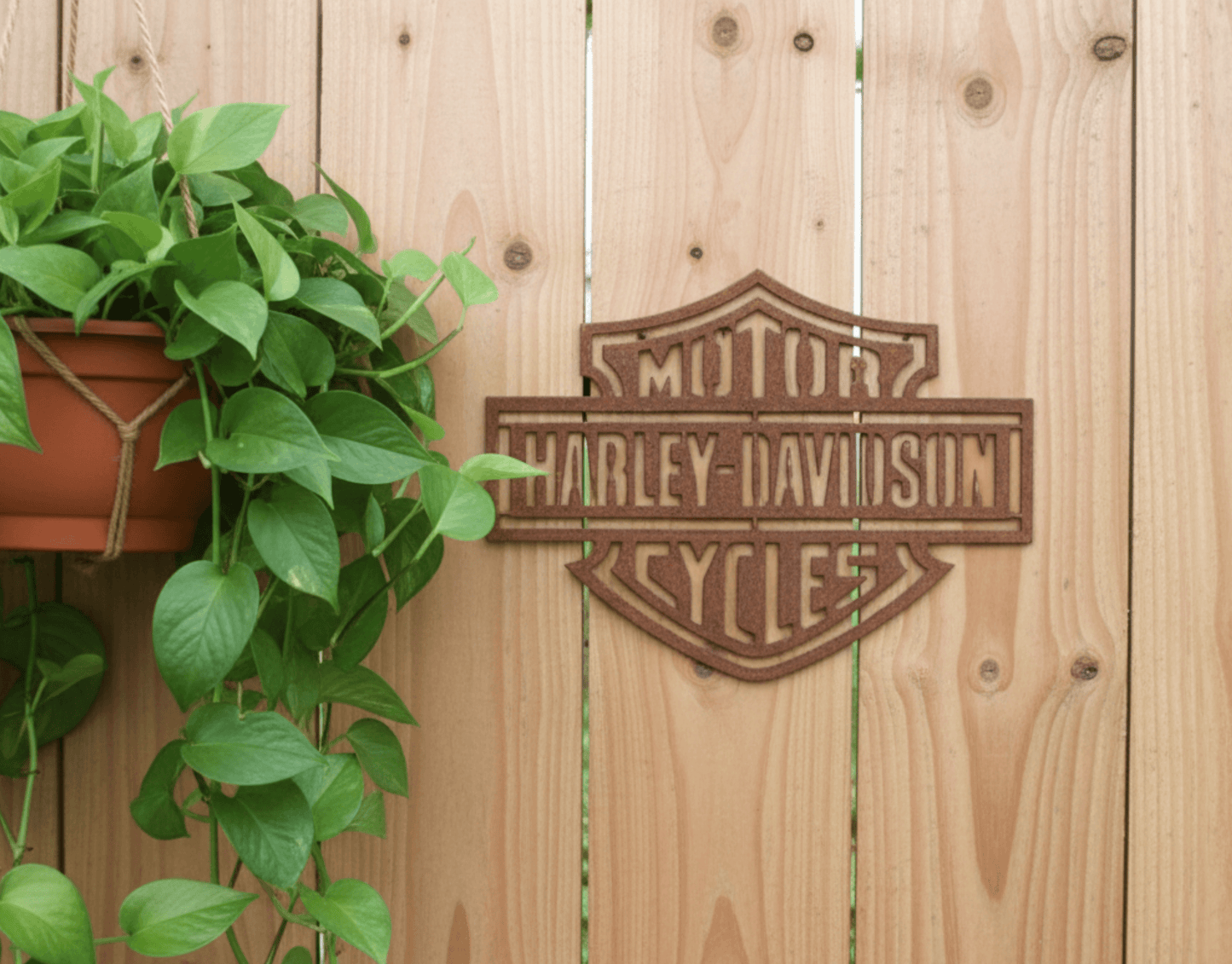 Rustic Metal Harley Davidson Motorcycle Badge Sign on a wooden background with a plant.