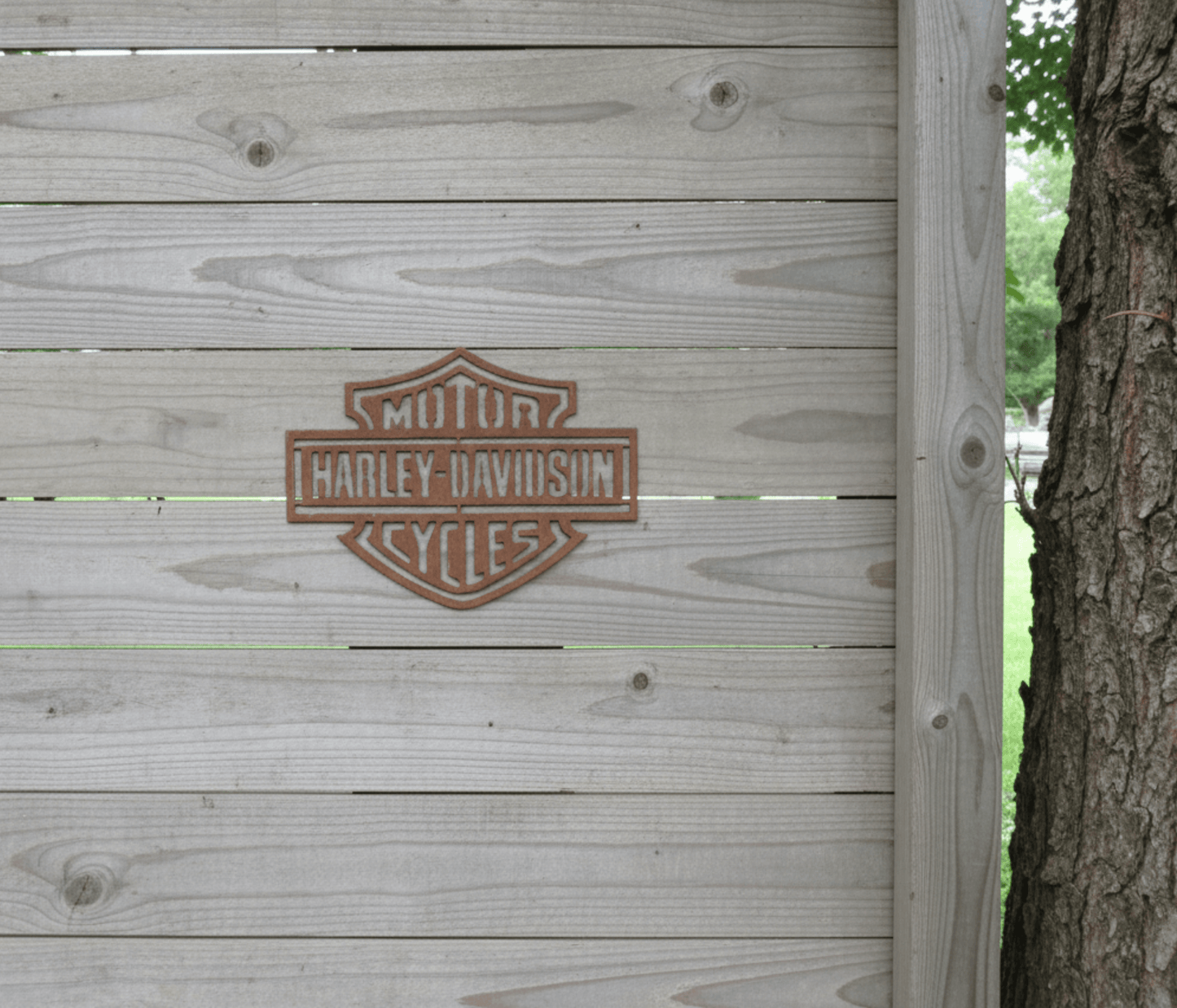 Rustic Metal Harley Davidson Motorcycle Badge Sign on a wooden fence beside a tree