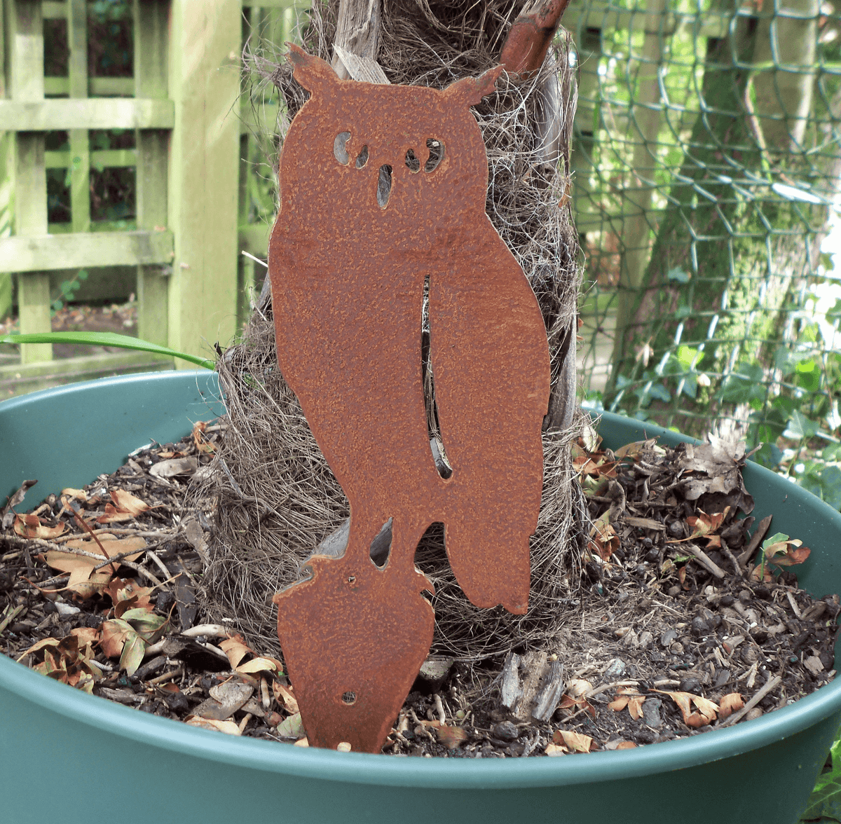 Rusted steel owl garden ornament displayed in a flower pot, showcasing its rustic charm and unique patina finish.