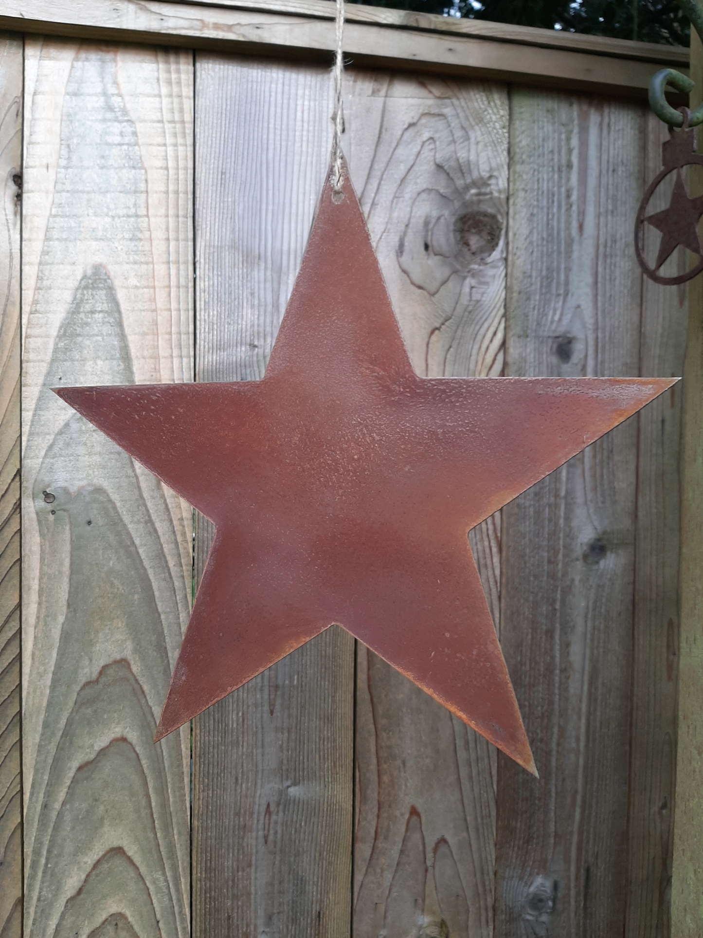 Rusty Metal STAR Garden Ornament  hanging on a wooden fence