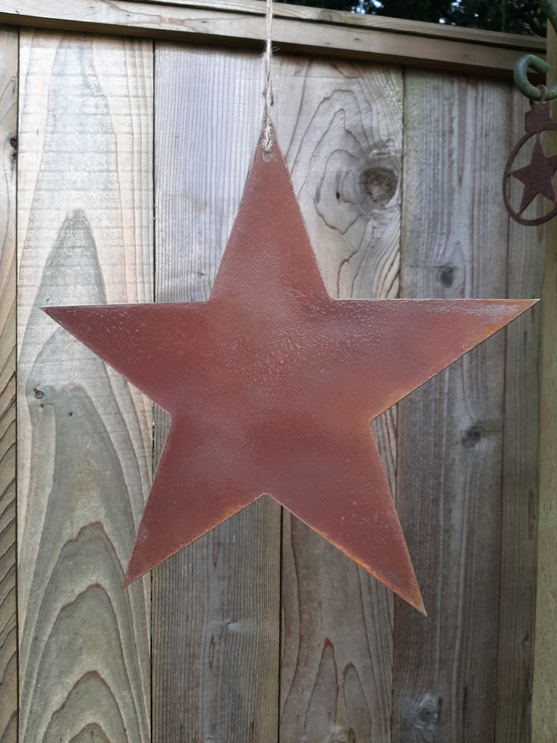 Rusty Metal STAR Garden Ornament  hanging on a wooden fence