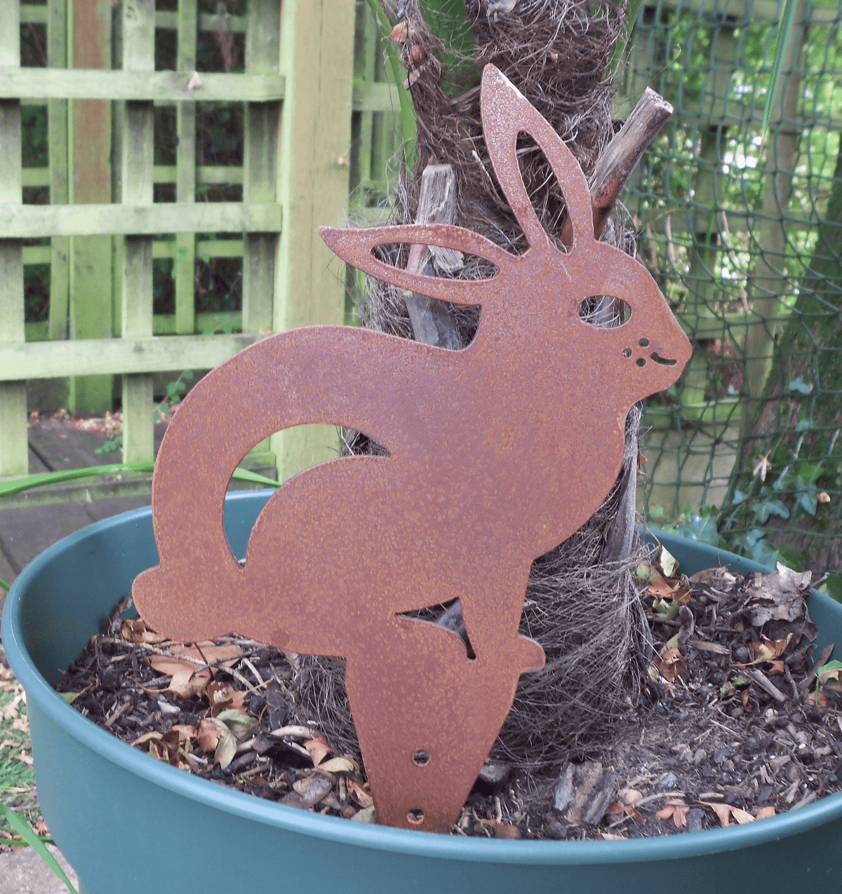 Rusted Steel RABBIT Garden Ornament in a planter, showcasing unique patina, rustic metal yard art.