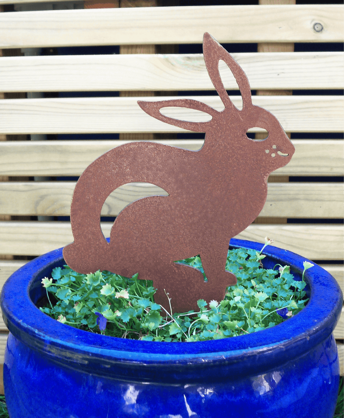 Rusted Steel RABBIT Garden Ornament placed in a blue pot with greenery, showcasing rustic metal decoration.