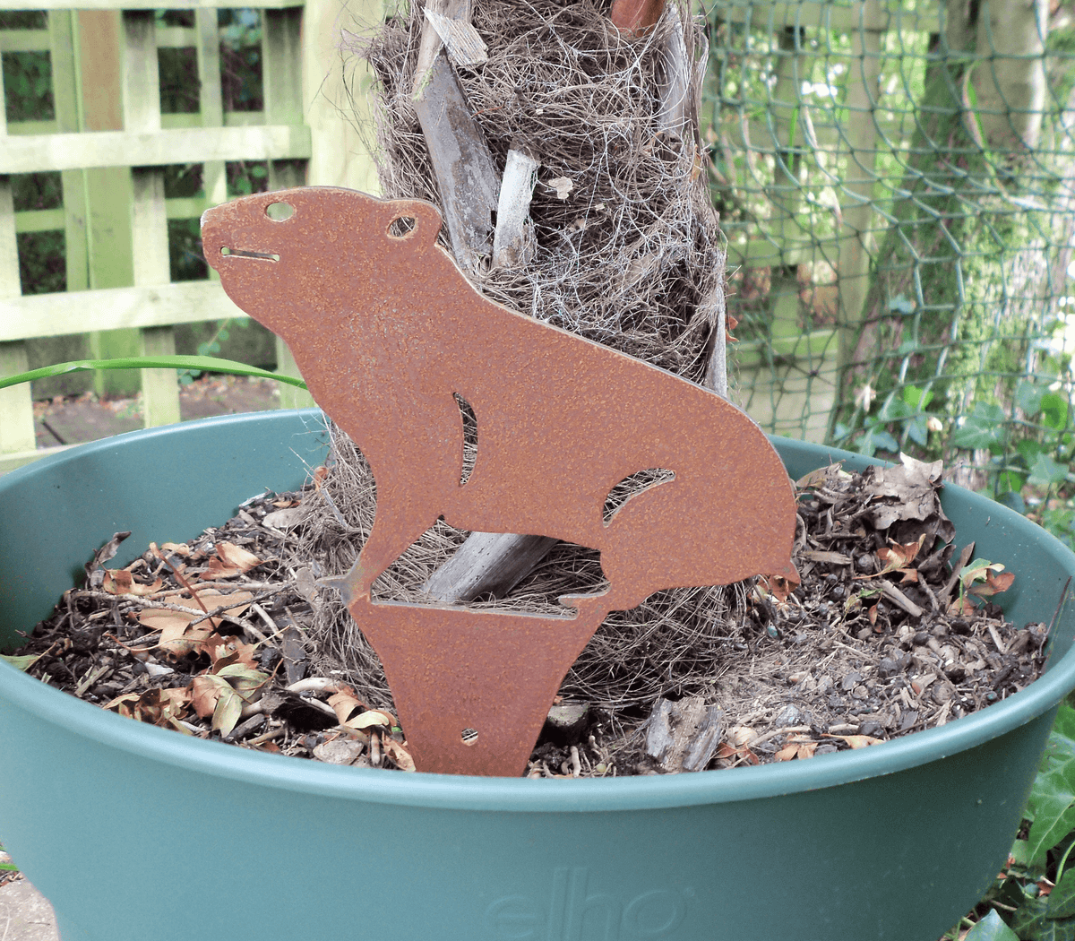 Rusty Steel HAMSTER Garden Ornament displayed in a planter, showcasing unique rusted metal design for garden charm.