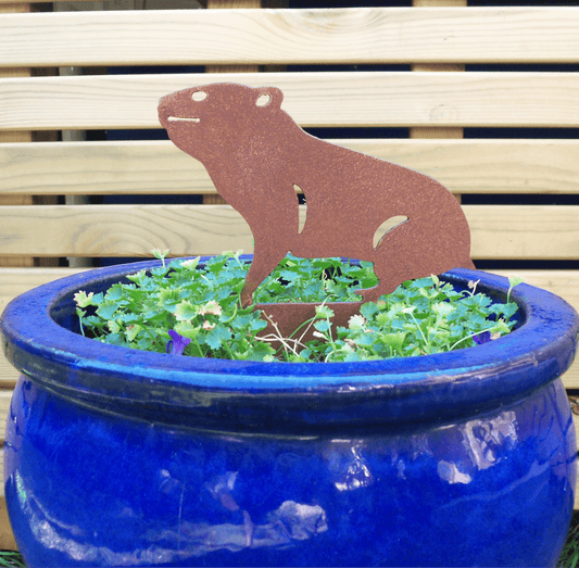 Rusty Steel HAMSTER Garden Ornament placed in a blue pot with greenery, adding rustic charm to the garden.