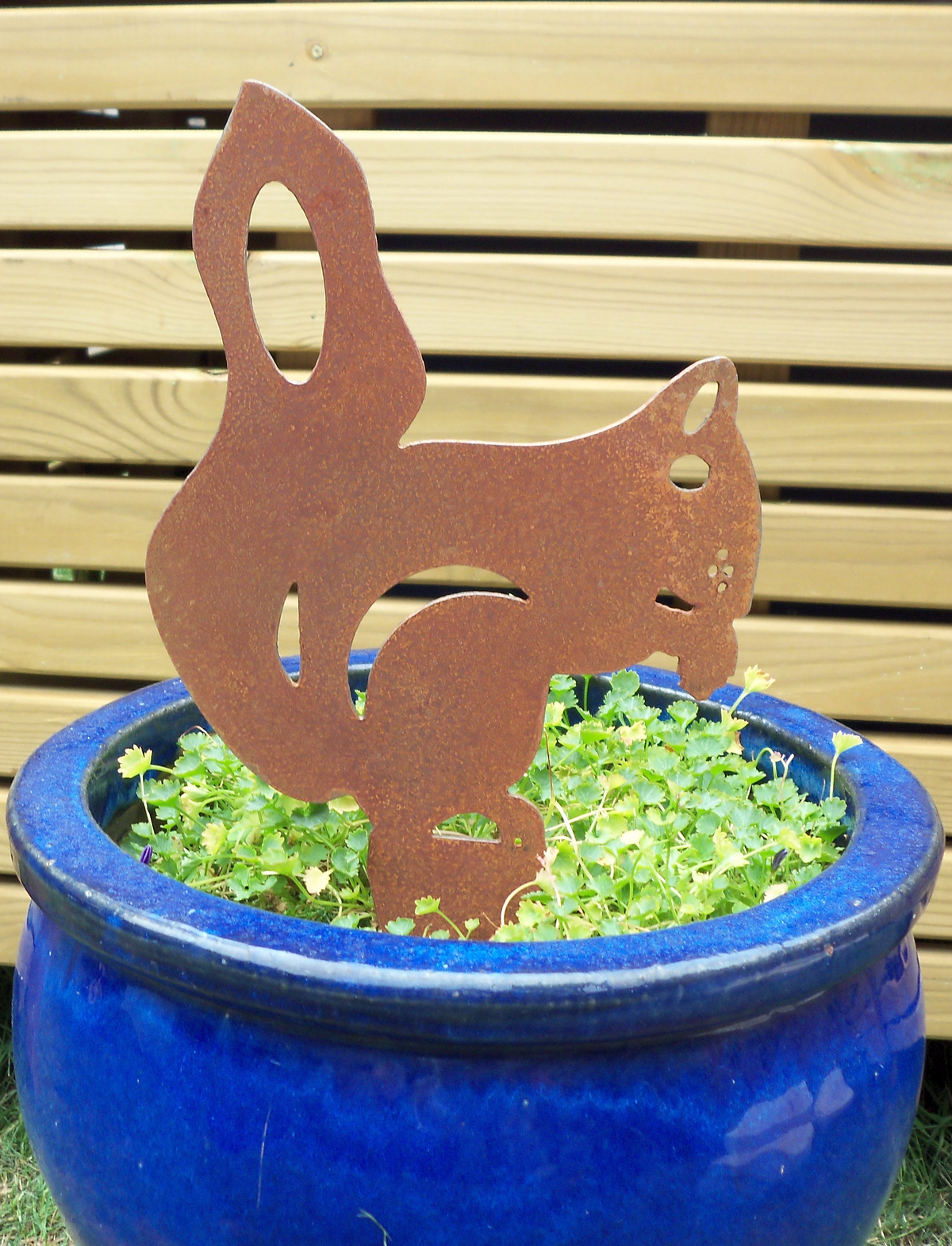 Rusty Steel Squirrel Garden Ornament displaying a unique rustic metal design in a blue pot filled with greenery.