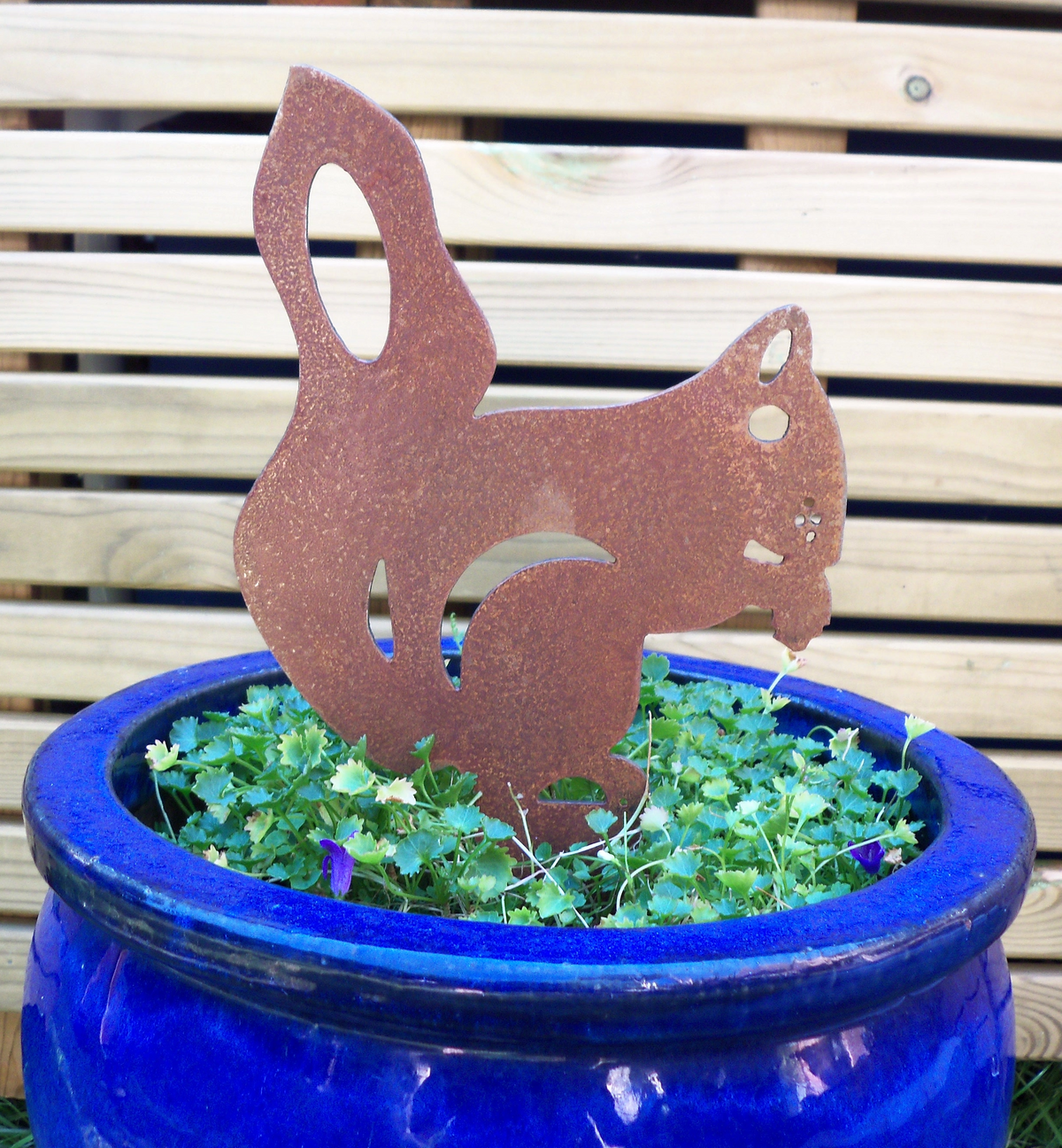 Rusty Steel Squirrel Garden Ornament in a blue pot surrounded by greenery, ideal rustic metal garden decoration.