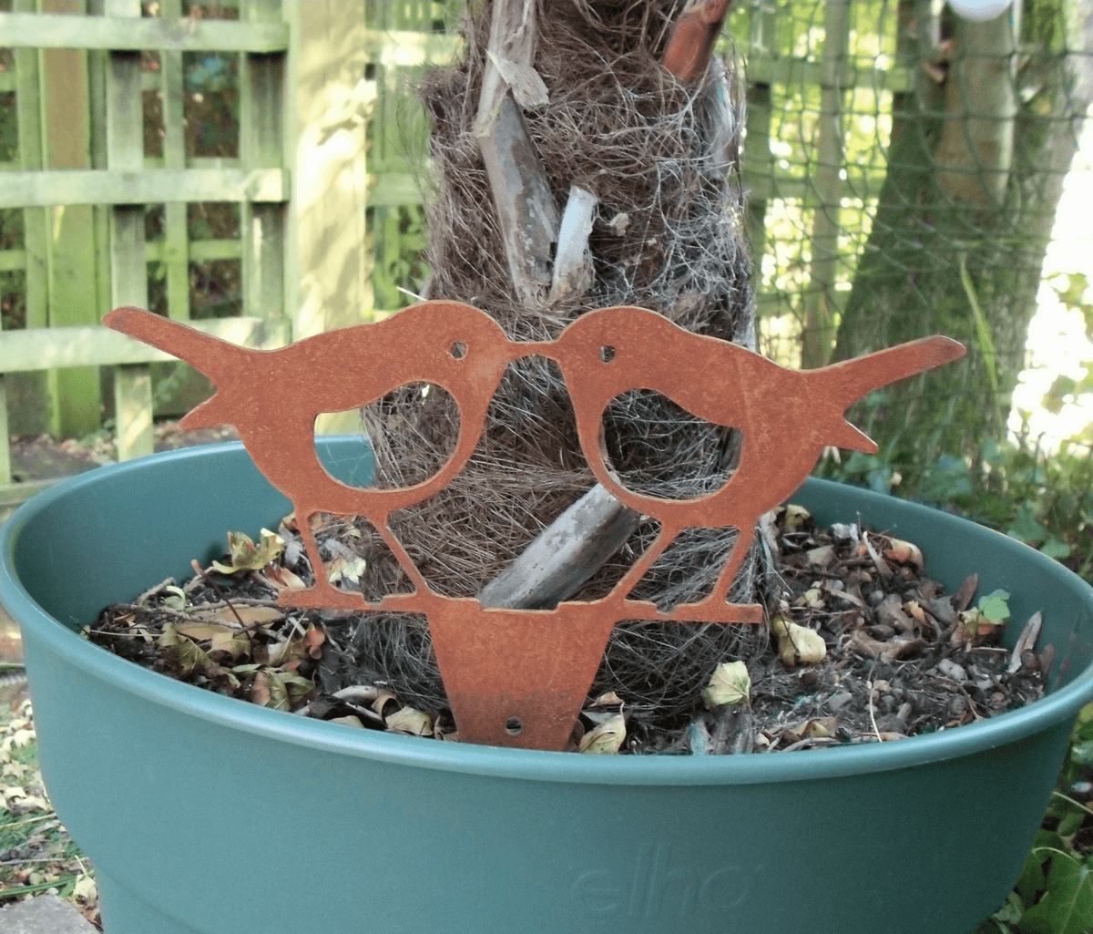 Rusty steel kissing robins garden ornament in a pot, showcasing a unique rustic design for garden decoration.