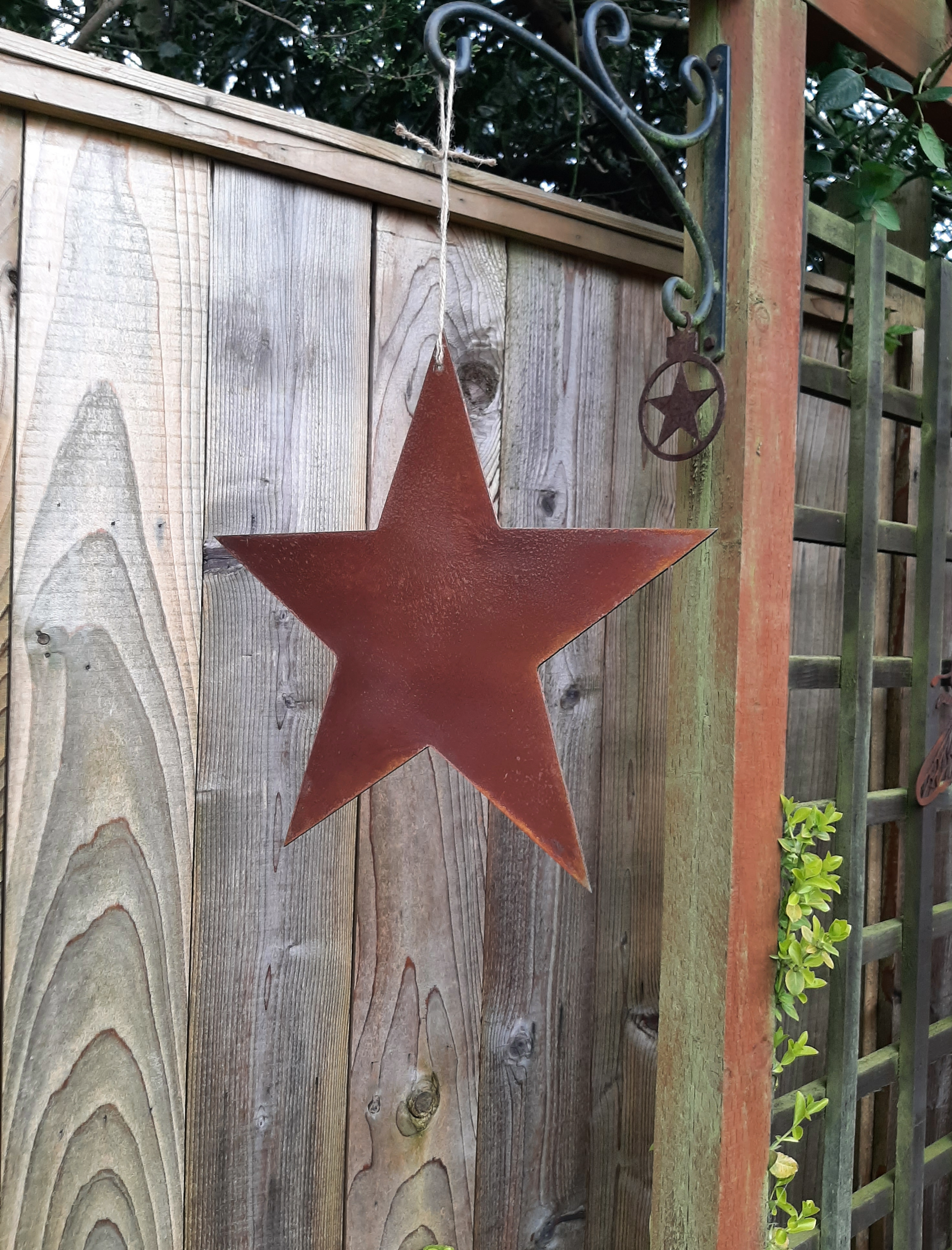 Rusty Metal STAR Garden Ornament  ornament hanging on a wooden fence
